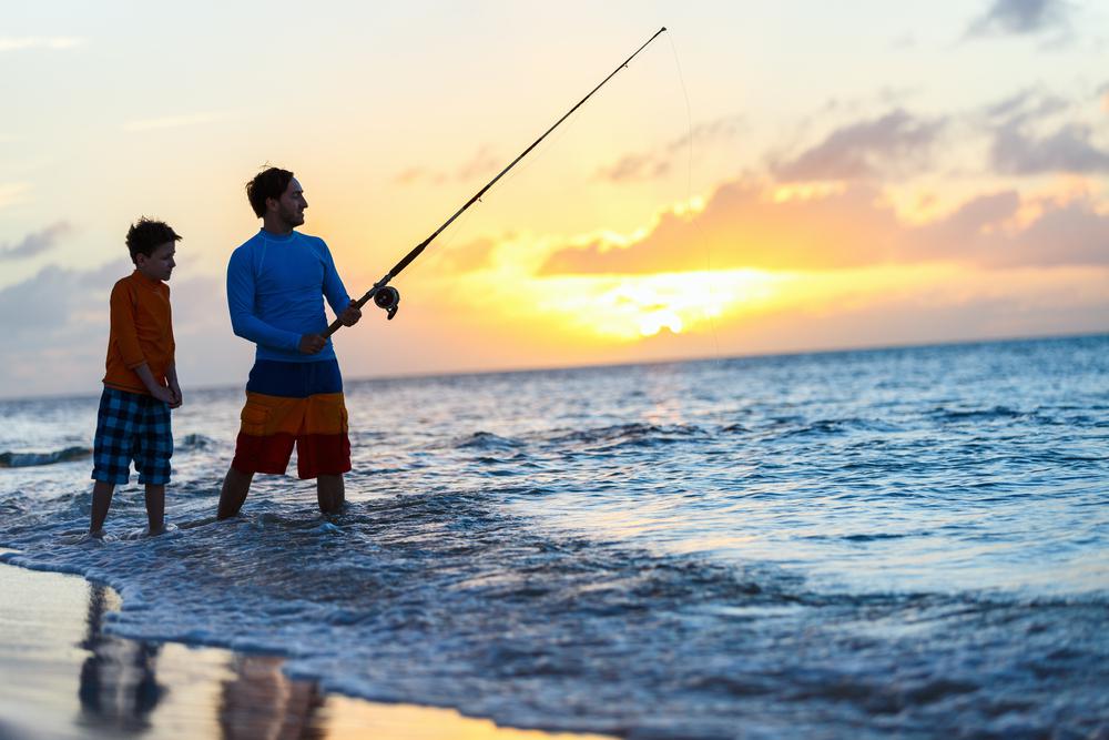 Father and son fishing on the beach.