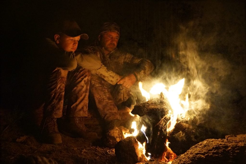 Elk hunters sitting around a campfire.