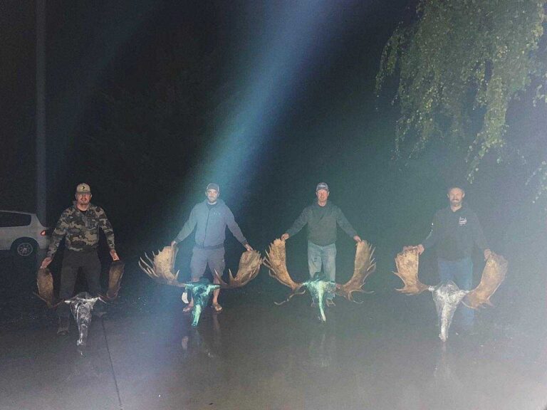 Ben Bechdolt — four hunters with bull moose antlers at night (Alaska, 2021)