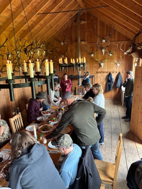 Clifford Howard — hunting lodge dinner gathering with trophy mounts (Scotland, 2026)
